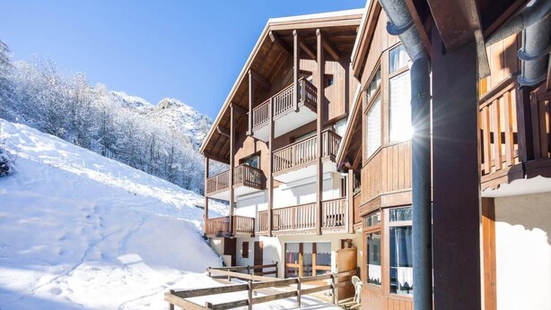 A wooden chalet with balconies, a wooden fence, and a snowy mountain backdrop. - 150m from ski slopes, Ground floor, terrace, parking, tv, 27m², Valloire (Valloire)