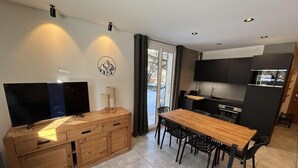 A modern kitchen with a wooden dining table and chairs, a built-in oven, and a large flat-screen TV on a wooden cabinet. - 350m from ski slopes, 2nd floor, sauna, terrace, ski locker, 41m², Valloire (Valloire)