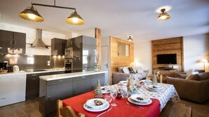 Une cuisine moderne avec des meubles de couleur sombre, un îlot central et des luminaires suspendus.