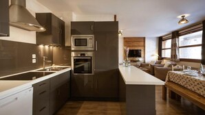 Une cuisine moderne dotée d’appareils électroménagers intégrés, d’un îlot central et d’un coin repas offrant une vue agréable.
