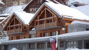 Una fila di edifici in stile chalet in legno con balconi, coperti di neve, che indica un contesto invernale.