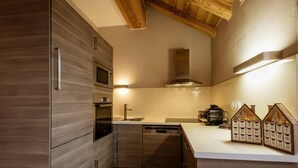 Una cocina moderna con armarios de madera, electrodomésticos integrados y una lámpara de estilo campestre.