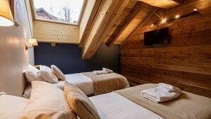 Una habitación tipo cabaña acogedora con dos camas, un tragaluz, paredes de madera y un televisor montado.