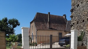 A gated entrance to a house with a stone wall and a metal gate.