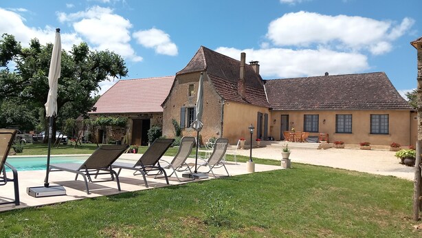 A house with a swimming pool, outdoor seating, and a garden.