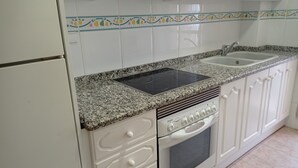 A kitchen with white cabinets, a granite countertop, a built-in oven, and a double sink.