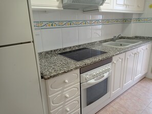 A kitchen with white cabinets, a granite countertop, a built-in oven, and a double sink.