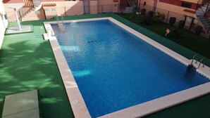 A rectangular pool with a white edge, surrounded by a green deck.