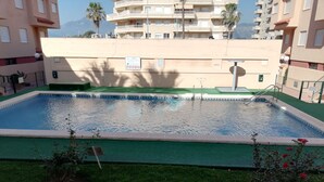 Ein Swimmingpool mit grüner Poolterrasse, umgeben von Gras und kleinen Pflanzen.