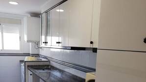 Eine Küche mit weißen Schränken, einer Granit Arbeitsplatte, einem Backofen und einer Mikrowelle.