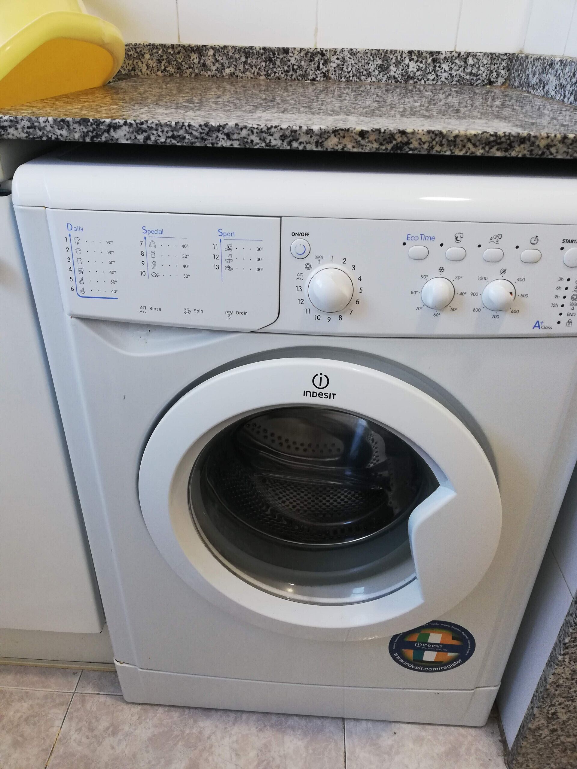 A front-loading washing machine with a control panel, a digital display, and a brand logo.