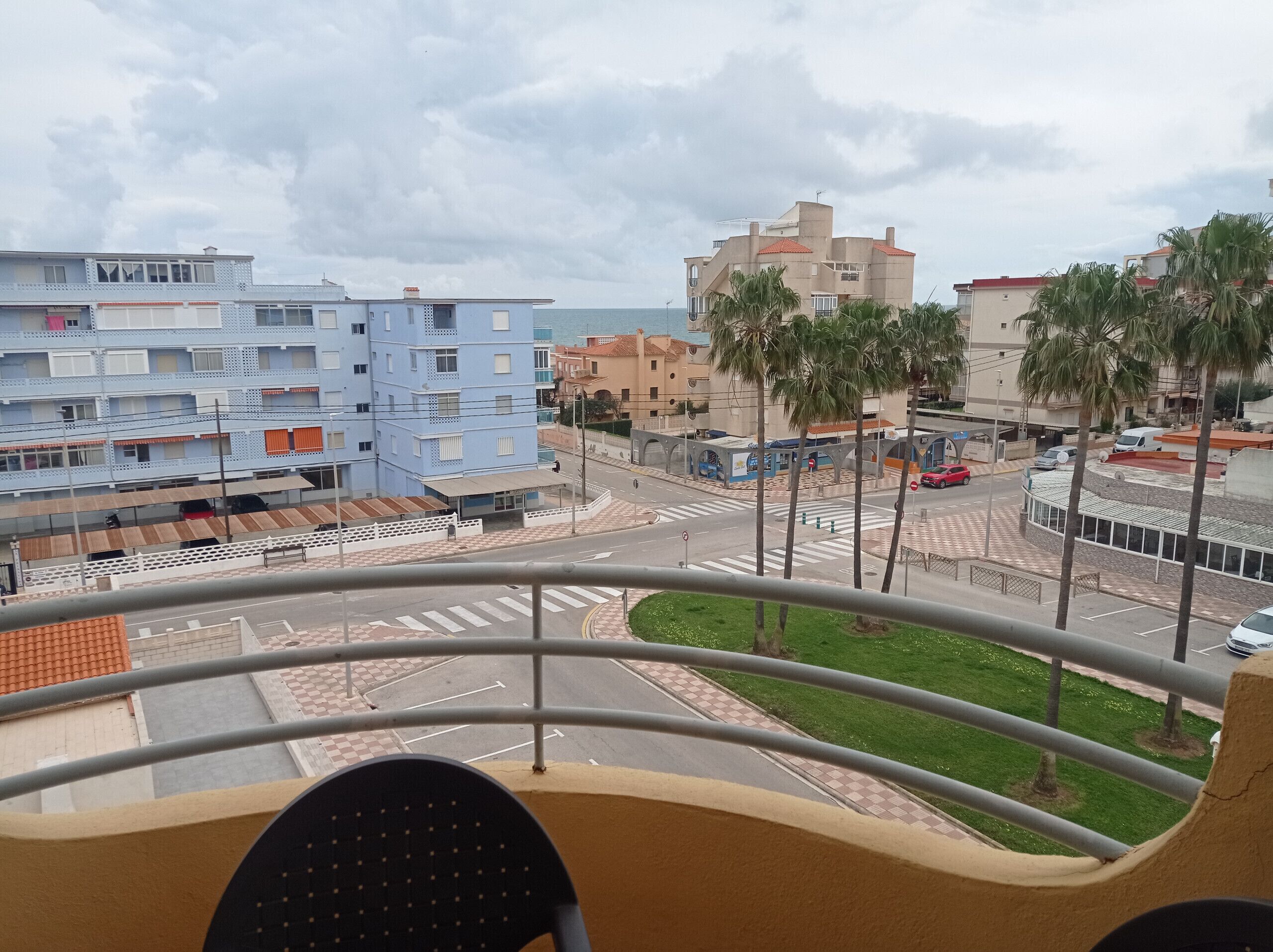 Un balcón con vista a un paisaje urbano, incluyendo edificios y una carretera.