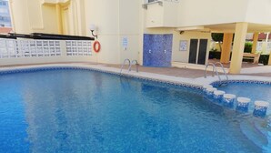 Una piscina con agua azul cristalina, un flotador salvavidas y una pared de azulejos con un diseño de mosaico azul.