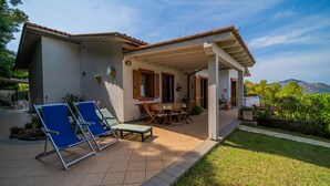 A covered patio with outdoor furniture, a dining table, and potted plants. - Appartamento Villa da 4 Fino a 5 Persone Giardino (Capoliveri)