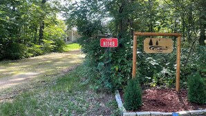 A sign for Cedarwood Cottage with a red 'N1148' sign and a wooden signboard. - Cheerful cottage w/ fireplace. Great location for exploring the Lake Pepin area! (Pepin)