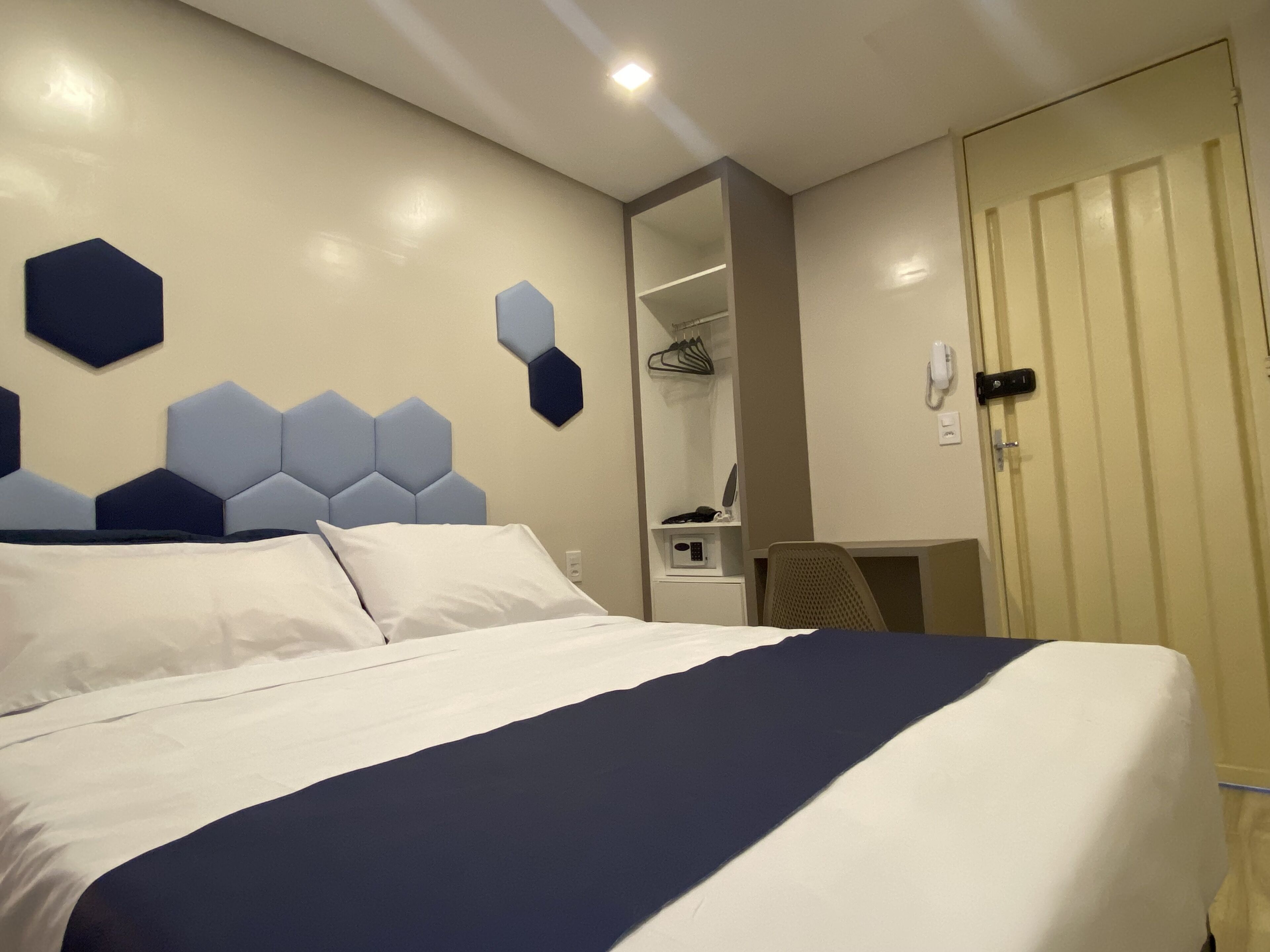 Une chambre d’hôtel avec un grand lit, une armoire, un bureau et un miroir.