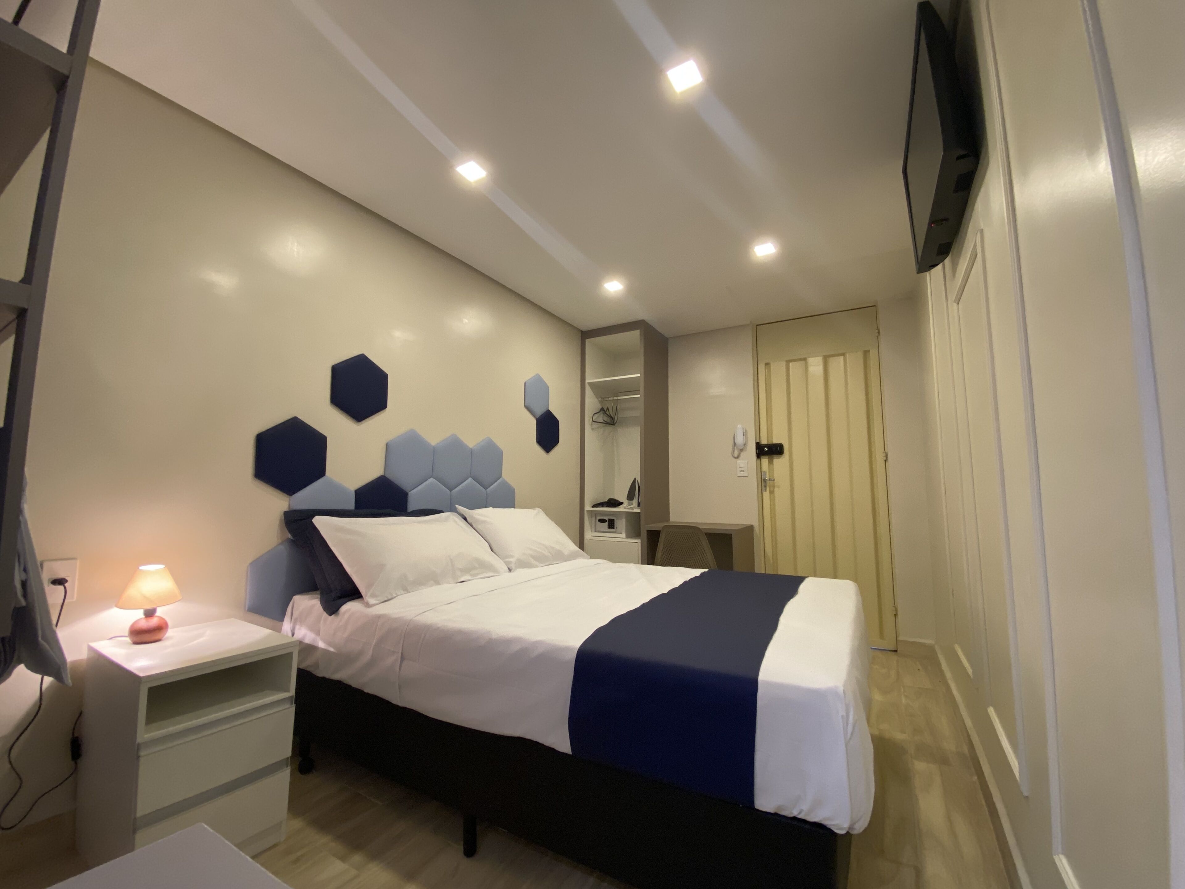 Une chambre d’hôtel équipée d’un lit, d’une table de chevet, d’une lampe et d’un téléviseur fixé au mur.