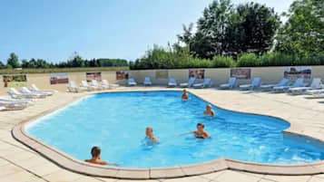 Una piscina con lettini e persone che nuotano.