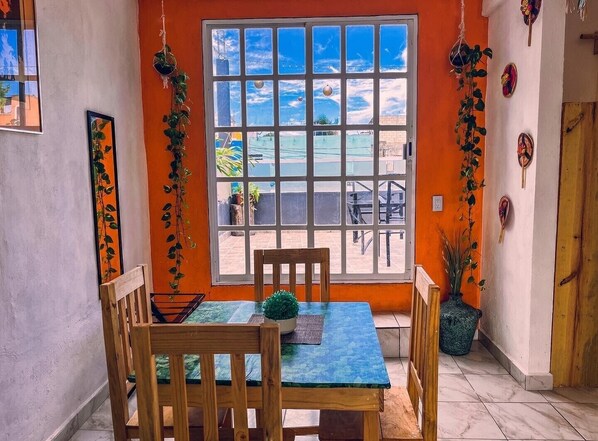A dining area with a table and chairs, a window with a view of the outside, and decorative items on the walls.