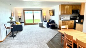 A spacious living area with a sofa, a dining table, and a kitchen area with wooden cabinets and appliances. - Relaxing Ranch Style Waterfront Home--30 minutes from Ann Arbor (Pinckney)