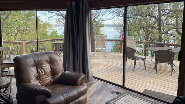 A room with a large window overlooking a deck with outdoor furniture. - Beautiful, Majestic Log Cabin Large Game Room and Lake View (Wagoner)