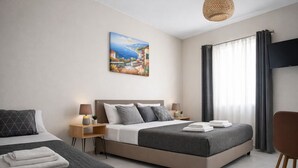 Une chambre d’hôtel avec deux lits, un tableau, une télévision et une fenêtre avec des rideaux.