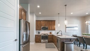 Una cucina moderna con elettrodomestici in acciaio inox, mobili in legno e luci a sospensione.