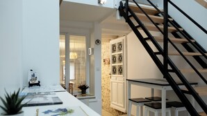 A modern kitchen with a long countertop, a staircase, and a view into the dining area. - GITE DU SUD DE L'AISNE Rated 3 stars by Aisne tourisme. (Hautevesnes)