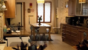 A modern kitchen with a dining area, featuring a wooden table, chairs, and a built-in microwave. - GITE DU SUD DE L'AISNE Rated 3 stars by Aisne tourisme. (Hautevesnes)