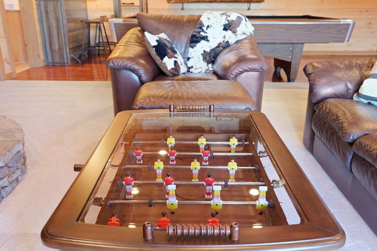 Una mesa de fútbol de mesa en una habitación con sofás de cuero y una mesa de billar.