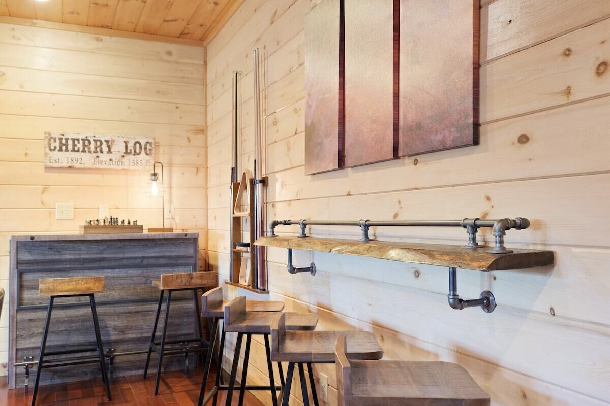 Un área de bar rústica con taburetes de madera, una barra y un letrero que dice 'CHERRY LOG'.