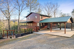 A rustic cabin with a covered porch, a deck, and a stone foundation.