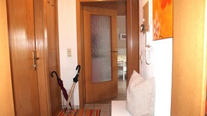 A hallway with wooden doors, a striped rug, a white sofa, and an umbrella leaning against the wall. - Comfortable apartment on the Zollernalb for families, single travelers, workers, .... (Meßstetten)