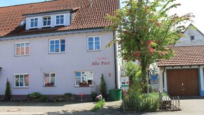 A building with a tiled roof, multiple windows, and a sign reading "FeWo Alte Post". - Comfortable apartment on the Zollernalb for families, single travelers, workers, .... (Meßstetten)