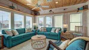 A cozy living room with a sectional sofa, a round coffee table, and a ceiling fan. - Pool-Top Home-Walk to Town! (Port Aransas)