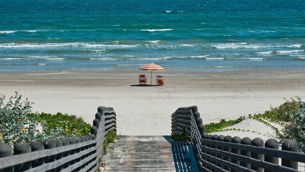 A beach with a pathway leading to a seating area with an umbrella. - Pool-Top Home-Walk to Town! (Port Aransas)