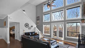 Amplia sala de estar con un sofá modular grande, una mesa de centro y una chimenea. Varias ventanas ofrecen luz natural y vistas al exterior.