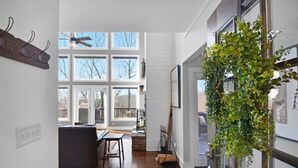 Una cocina amplia con grandes ventanales, suelo de madera y una planta colgante.