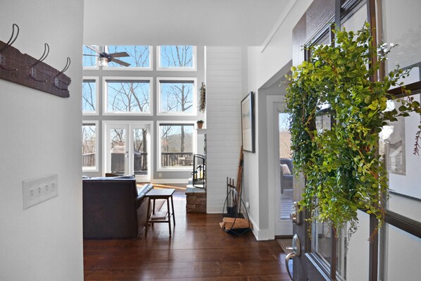 A spacious kitchen with large windows, wooden flooring, and a hanging plant.