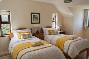 Una camera da letto con due letti, ciascuno con comodino e lampada, un quadro appeso al muro e una finestra con tende.