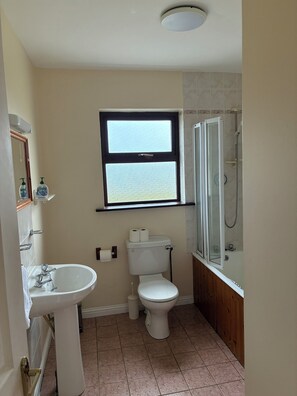 Un bagno con lavandino, WC, finestra e doccia.