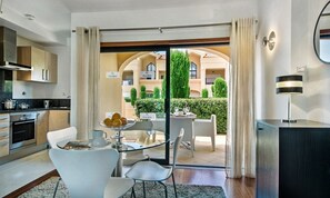 Cozinha moderna com área de refeições, uma grande porta de vidro deslizante que dá para um pátio externo com vista para um edifício identificado como