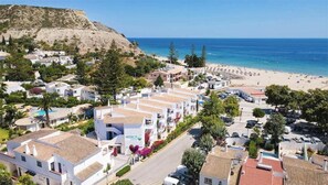 Uma cidade costeira com edifícios brancos, uma praia e uma montanha ao fundo.