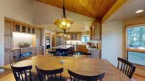 Une cuisine spacieuse avec des meubles en bois, un îlot central doté de sièges et une grande table à manger.