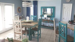 A dining area with a table and chairs, a mirror, and a clock on the wall. - Beachside Blessings (1 Block From the Beach!) (Mexico Beach)