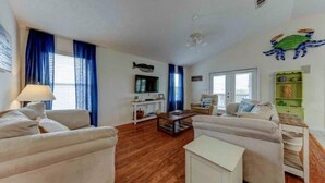 A living room with two sofas, a coffee table, a TV, and a bookshelf. - Beachside Blessings (1 Block From the Beach!) (Mexico Beach)