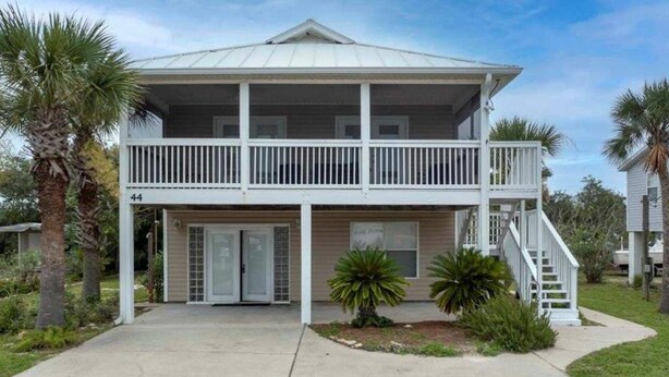 A two-story house with a balcony, a front door, and a staircase leading to the second floor. - Beachside Blessings (1 Block From the Beach!) (Mexico Beach)