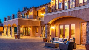 A multi-story building with stone pillars, outdoor seating, and a balcony.