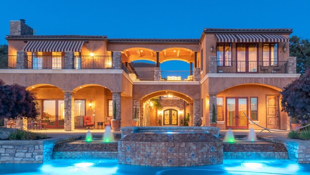 A large, multi-story house with a swimming pool and a fountain.