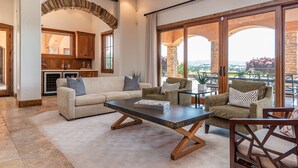 A spacious living area with a large window, a fireplace, and a stone archway.